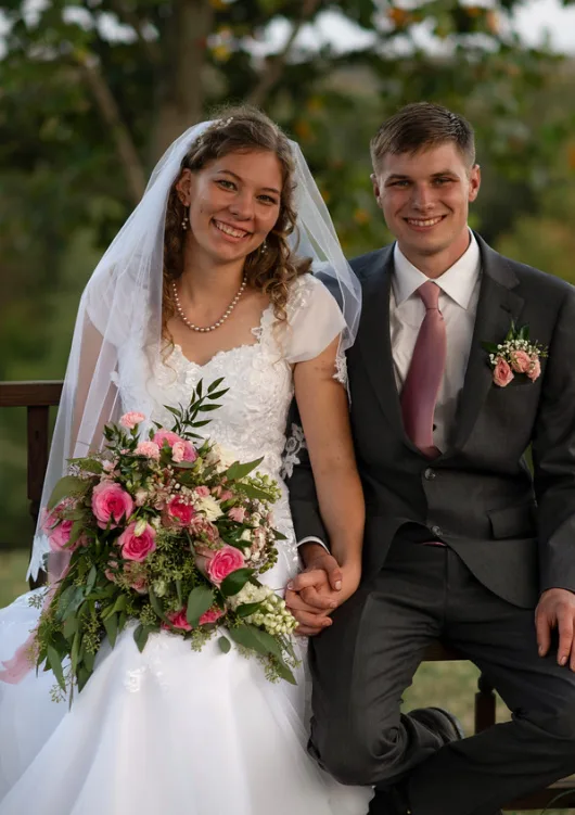 Newlywed couple holding a cascading pink rose bouquet